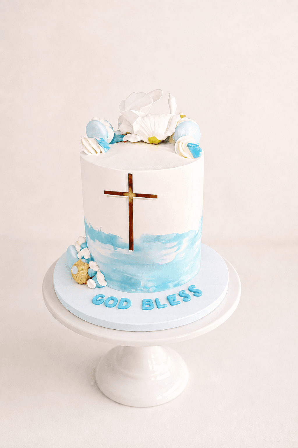 Blue and white christening cake with a cross and 'God Bless' lettering by Glory Treats